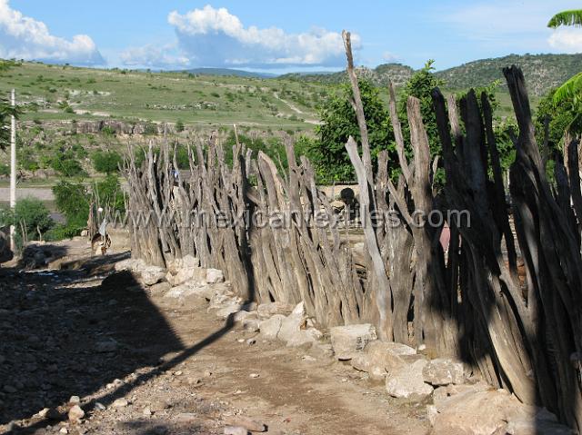 nahuatl_analco81.JPG - Wood fence , the river below and the hillside on the opposite side of the river with little or no trees.