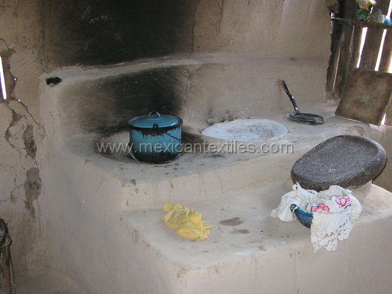 muralitas_casa_01.JPG - Documentation of tepehuano indigenous textiles from Huajicori, Nayarit, Mexico. Tepehuano kitchen with the fire outside the house to avaoid smoke inside the home. On the floor to the left is a deer skin stool , which we encountered throughout the area.