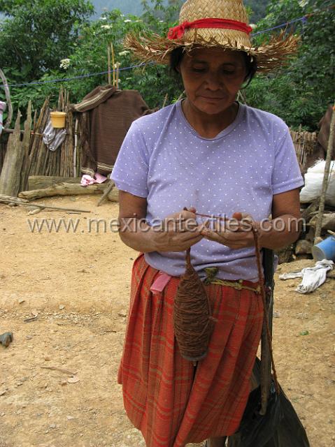 nahua_tecapagco_12.JPG - spinning wool, in the background on the fence is a sample of a blanket made from wool spun in the village.